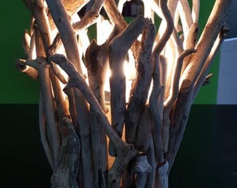 May include: A unique lamp crafted from driftwood, featuring a warm, inviting glow. The lamp is constructed from numerous pieces of weathered wood, arranged to create an organic, sculptural form. The base is a circular piece of wood.