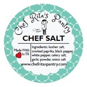 May include: A round, teal-colored label with a white border and a white design. The label says "Chef Rita's Pantry" in a white cursive font. The label also says "Chef Salt" in a larger white font. The label lists the ingredients: kosher salt, smoked paprika, black pepper, white pepper, celery salt, garlic powder, and onion salt. The label also includes the website address: www.chefritaspantry.com.