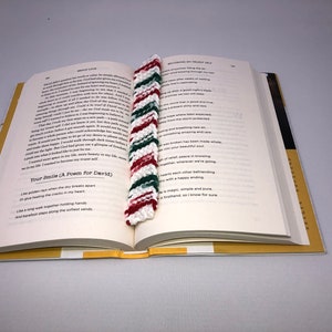 Może przedstawiać: Zbliżenie na książkę z czerwoną, białą i zieloną zakładką wykonaną na szydełku. Zakładka jest w paski i ma frędzle na dole. Książka jest otwarta na stronie z tytułem "Your Smile (A Poem for David)".