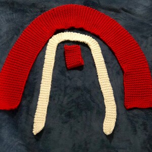 Może przedstawiać: Trzy dziane paski tkaniny w kolorze czerwonym i białym. Paski są ułożone w kształt półkola, z czerwonymi paskami na zewnątrz i białymi paskami wewnątrz.