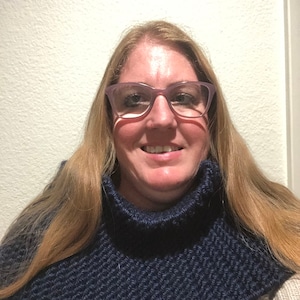 Może przedstawiać: Kobieta w niebieskim, dzianym kominie z golfem. Komin wykonany jest z fakturowanego splotu.