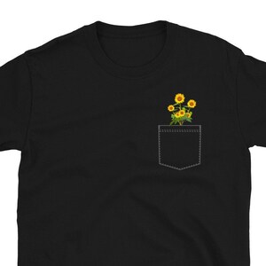 May include: Black t-shirt with a pocket featuring a small bouquet of yellow sunflowers.
