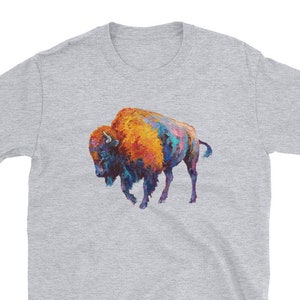 May include: A grey t-shirt with a colorful painting of a bison on the front. The bison is painted in shades of orange, blue, and purple.