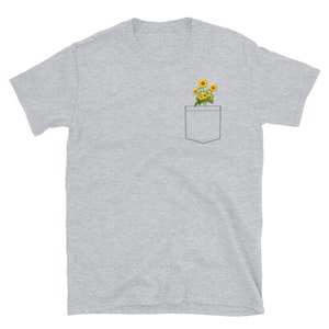 May include: A heather gray t-shirt with a pocket featuring a small bouquet of yellow sunflowers.
