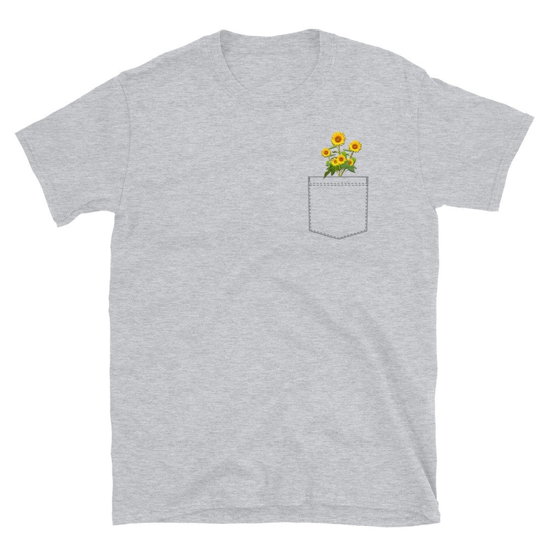May include: A heather gray t-shirt with a pocket featuring a small bouquet of yellow sunflowers.