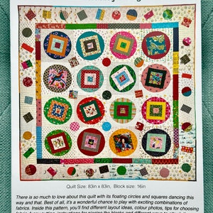 Puede incluir: Un patrón de edredón colorido titulado "Circle Boxes" de Rachaeldaisy Designs. El edredón presenta un diseño de círculos y cuadrados en varios colores y patrones. El tamaño del edredón es de 211cm x 211cm, con un tamaño de bloque de 40.6cm. El patrón incluye ideas de diseño e instrucciones.