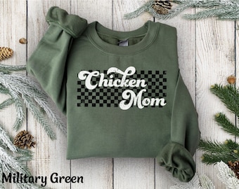 May include: Military green sweatshirt with the text "Chicken Mom" in a retro font over a black and white checkered pattern. The long-sleeved top is made of a soft material.