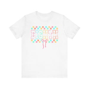 Puede incluir: Una camiseta blanca de manga corta con la palabra EIGHTH en una fuente de estilo universitario, con un borde de cuadros pastel encima y debajo del texto. Un pequeño lazo de cinta rosa está centrado justo debajo de la palabra EIGHTH al frente.