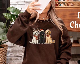 May include: A dark brown sweatshirt featuring a graphic of three dogs dressed for Christmas. One dog wears reindeer antlers and a scarf, another a Santa hat, and the third a red bow. The sweatshirt is a cozy, casual style.