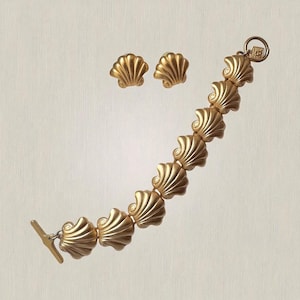 May include: A gold-toned jewelry set featuring a bracelet and matching earrings. The bracelet is composed of shell-shaped links, and the earrings are small shell studs. The set has a vintage aesthetic.