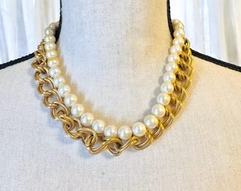 May include: A gold chain necklace with a strand of faux pearls. The necklace is layered with two chains, one thicker than the other.