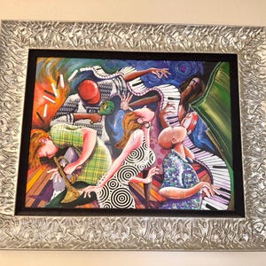 Puede incluir: Una pintura enmarcada que representa a un grupo de personas tocando música. La pintura es colorida y abstracta, con una mezcla de colores brillantes y líneas audaces. Las personas se representan de forma animada y enérgica, con sus cuerpos moviéndose al ritmo de la música. La pintura se sitúa sobre un fondo de teclado de piano, lo que sugiere un tema musical.