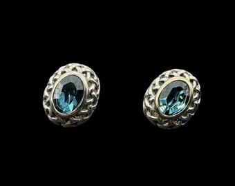 Può includere: Un paio di orecchini d'argento con una pietra preziosa di topazio blu incastonata in un design intrecciato.