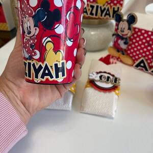 May include: Red and white paper cup with a Mickey Mouse and Minnie Mouse design. The cup has the name "Aziyah" printed on it.
