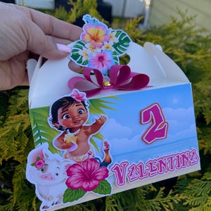 May include: A white party favor box featuring a cartoon illustration of a young girl, a pig, and a rooster. The box is decorated with tropical flowers, the number 2, and the name "Valentina". A pink bow and flower accents the top.