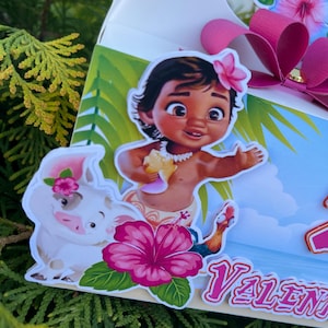 May include: A decorative gift box featuring cartoon characters and tropical flowers. The box has a pink bow and a cutout design. The characters include a girl with a flower in her hair, a pig, and a rooster. The word "Valent" is visible.