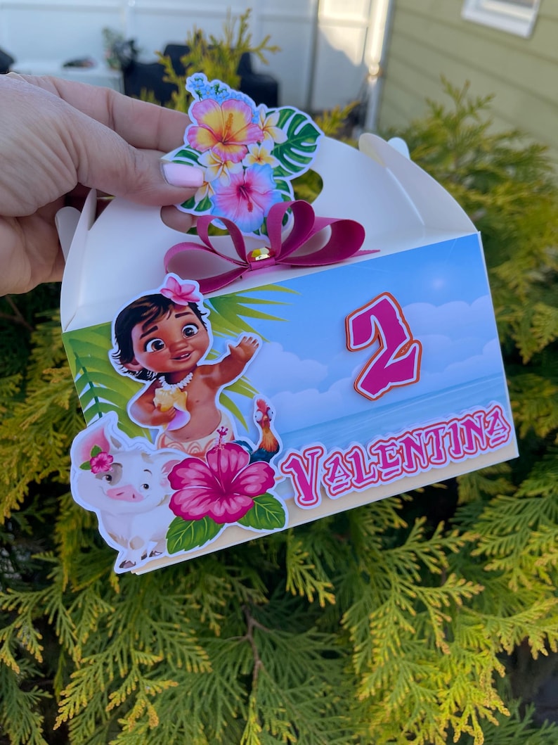 May include: A white party favor box decorated with a cartoon image of a girl, a pig, and a rooster. The box has a pink bow and the name "Valentina" with the number "2". Colorful floral stickers adorn the top.