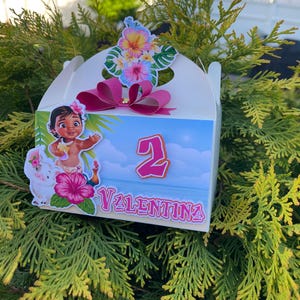 May include: A white gift box decorated with a cartoon image of a girl, a pink flower, and the name "Valentina". The box has a pink bow and a floral arrangement on top. The number "2" is also displayed.