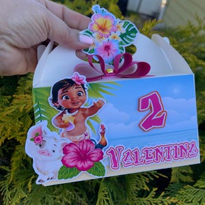 May include: A white party favor box with a tropical theme. The box features a cartoon illustration of a girl, a pig, and a rooster. The box is decorated with a pink hibiscus flower, the number 2, and the name "Valentina".