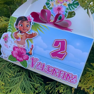 May include: A white gift box decorated with a cartoon image of a girl, a pig, and tropical flowers. The box features the number 2 and the name "Valentina" in pink. A pink bow and floral arrangement adorn the top.