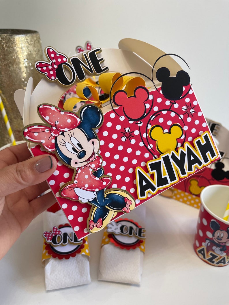 May include: Red and white polka dot party favor boxes with a Mickey Mouse and Minnie Mouse theme. The boxes are decorated with red and yellow balloons, a Minnie Mouse character, and the text "ONE" and "AZIYAH".