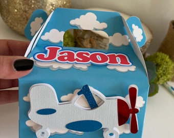 May include: A blue and white favor box with a white airplane and the name "Jason" on the front. The airplane has a red propeller and a blue number one on the side.