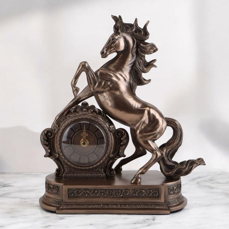 May include: Bronze-colored decorative clock featuring a rearing horse. The clock has an ornate, vintage design with a round clock face and Roman numerals. The horse statue is detailed and adds a touch of elegance to the home decor.