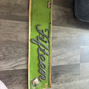 May include: A vintage "Fifteen" script number emblem on a green and tan backing. The emblem is silver-colored and made of durable plastic. The packaging includes text that reads "Easy mount", "Weatherproof", and "Rustproof".