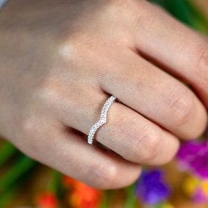 May include: A silver ring with a V-shaped band of small, clear stones.