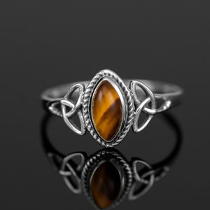 May include: A silver ring featuring a brown and gold tiger's eye gemstone set within a Celtic knot design.