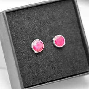 May include: A pair of silver stud earrings with pink gemstones set in a black velvet box.