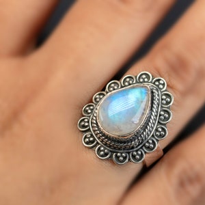 May include: A silver ring with a pear-shaped moonstone set in a decorative filigree design.
