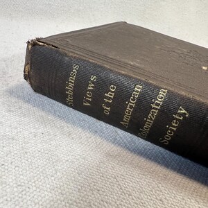 May include: A brown leather-bound book with gold lettering on the spine. The title is "Views of the American Colonization Society" by Stebbins.