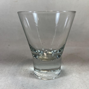 May include: A clear glass martini glass with a wide bowl and a thick base.