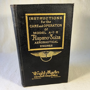 Puede incluir: Un libro negro con letras doradas titulado "INSTRUCTIONS For the CARE and OPERATION of MODEL A-I-E Hispano-Suiza AERONAUTICAL ENGINES" y un logotipo dorado alado con el texto "Wright-Martin Aircraft Corporation".