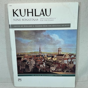 Op de afbeelding: Een bladmuziekboek getiteld "KUHLAU" met "Nine Sonatinas" en "Opus 20 & Opus 55 For The Piano" gedrukt op de omslag. De omslag toont een landschapsschilderij van een Europese stad. Het boek is een Alfred Masterwork Edition.