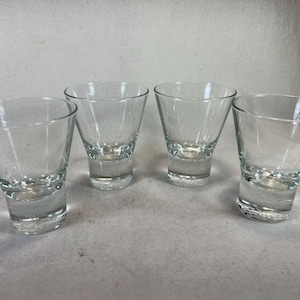Peut inclure: Quatre verres à shot en verre transparent avec un fond arrondi et une large ouverture.