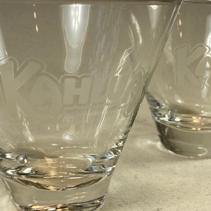 May include: Two clear glass cocktail glasses with the word "Kona" etched on the side.