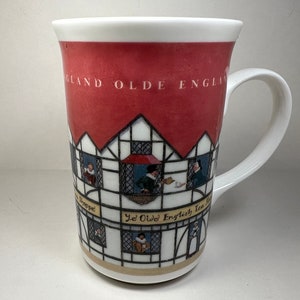 May include: A white ceramic mug with a red, white, and black illustration of a building with the text "Old England Tea Room" and "Ye Olde English Tea Room".