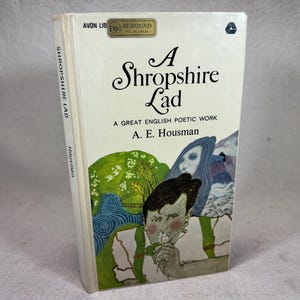 Pode incluir: Um livro branco com uma ilustração azul e verde na capa. O título é "A Shropshire Lad" e o autor é "A. E. Housman".