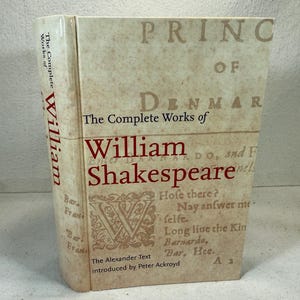 May include: A hardcover book titled "The Complete Works of William Shakespeare." The book has a cream-colored cover with red lettering and decorative elements. The spine displays the author's name in red.