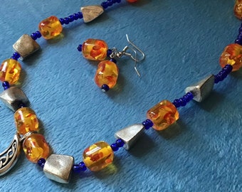 Moon pendant necklace set with orange and blue beads. Moon pendant with Celtic-like design and silver colored beads.
