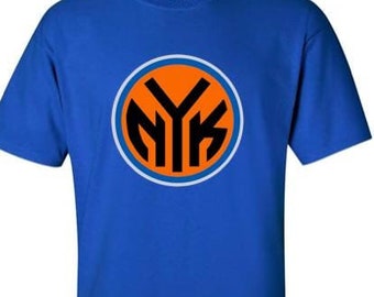 Op de afbeelding: Een koninklijk blauw t-shirt met een cirkelvormig logo met de letters "NYK" in zwart op een oranje achtergrond. Het logo wordt omringd door een witte en blauwe ring.