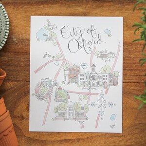 May include: A hand-drawn map of the City of Oxford, featuring landmarks like the Oxford Square, the campus, and the various parks. The map is drawn in a whimsical style with colorful lines and illustrations.