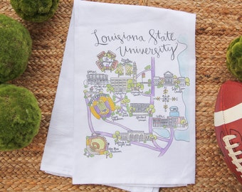 Może przedstawiać: Biały ręcznik kuchenny z ręcznie narysowaną mapą Louisiana State University. Mapa zawiera budynki uniwersyteckie, zabytki i obiekty sportowe. Tekst "Louisiana State University" jest napisany kursywą u góry ręcznika.