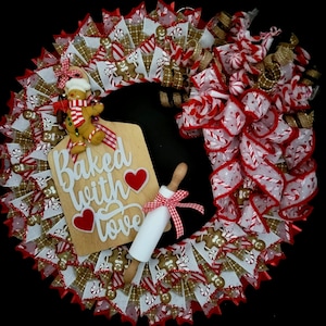 May include: A Christmas wreath decorated with red and white ribbon, gingerbread men, and a wooden sign that says "Baked with love".