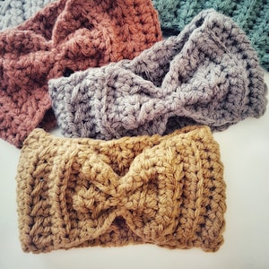 May include: Four crocheted headbands in different colors: brown, gray, light brown, and teal. The headbands are made with a twisted knot design.
