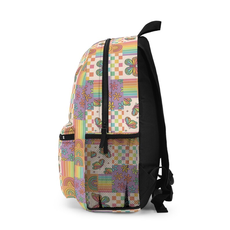May include: A side view of a black backpack with a colourful patchwork design. The design features rainbows, butterflies, flowers, and checkered patterns in shades of pink, yellow, orange, and purple.