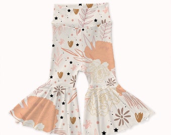 May include: White bell bottom pants with a floral and star print in shades of pink, brown, and gold.