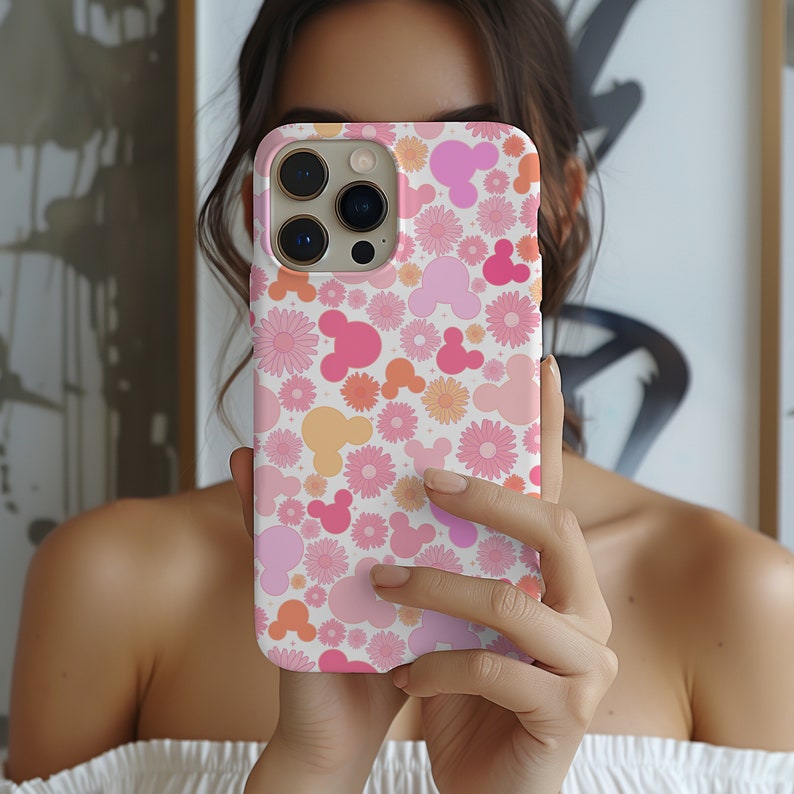 May include: A pink and white phone case with a pattern of pink and orange Mickey Mouse heads and pink flowers.